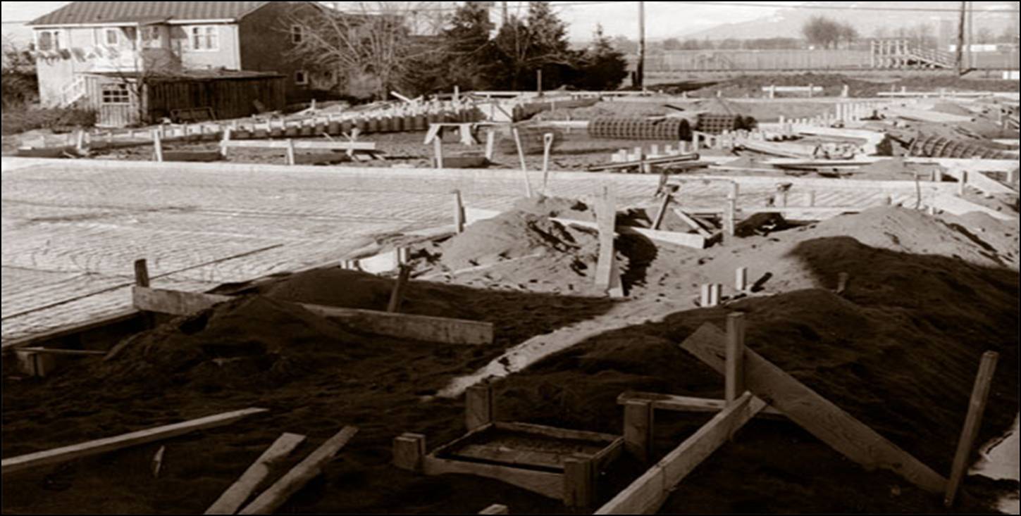 Historic black and white photograph of the initial construction phase in 1955, showing the excavated site and early foundation work for the church's first permanent building in Richmond.