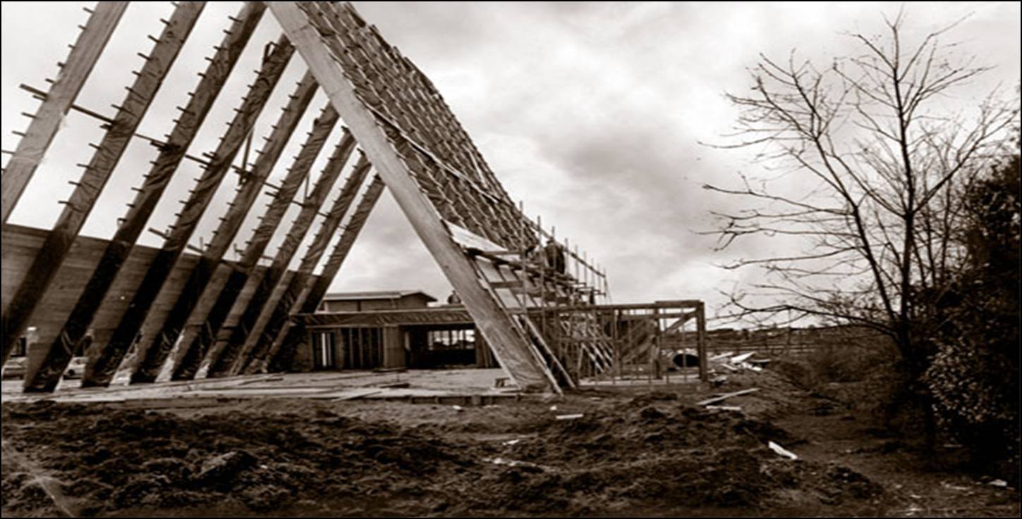 1964  historic photograph of workers on scaffolding beginning exterior work on the steep A-frame skeleton of Trinity Lutheran Church in Richmond. The large triangular structure stands against a cloudy sky on the southern horizon.