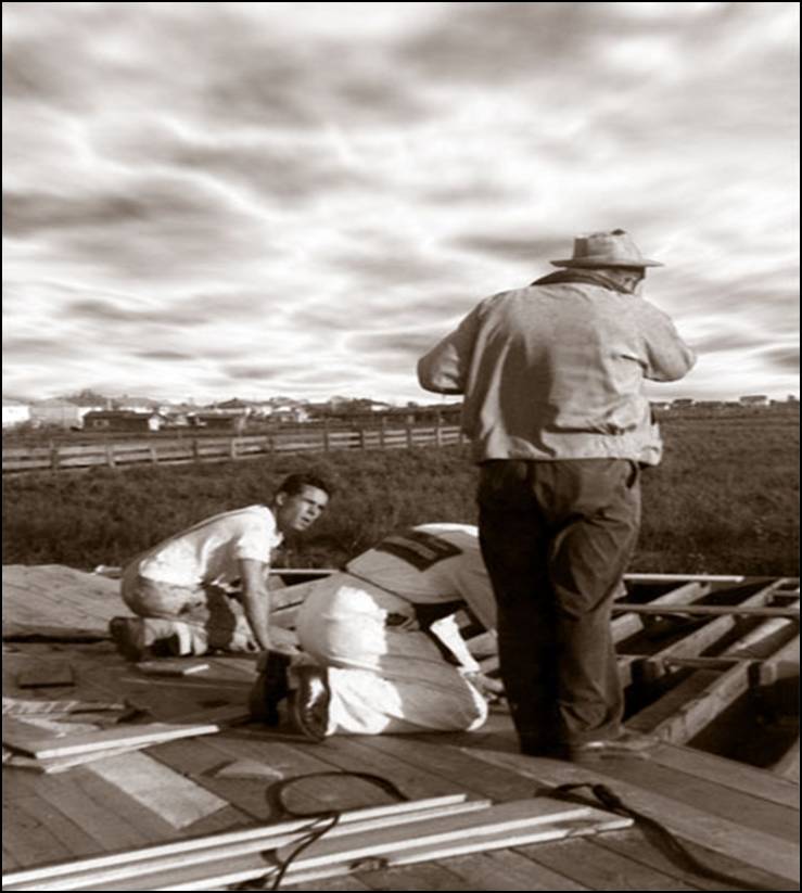 A historic black and white photograph from 1964 showing the early construction phase for the new A-frame Trinity Lutheran Church in Richmond. The Brighouse area and open fields are visible in the distance with three men working in the foreground.