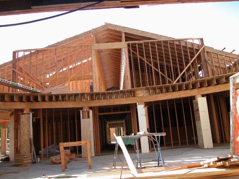 A photograph showing the complex interior wooden framing for the multi-use facility at Trinity Lutheran Church in Richmond, BC. The image highlights the second-floor joists, supporting columns, and the pitched roof framing of the upper level.