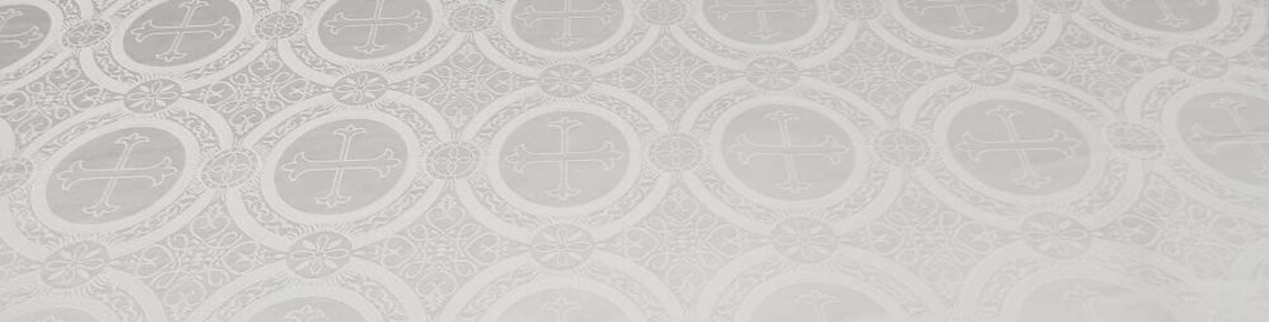 A close-up of white liturgical brocade fabric with woven crosses and floral motifs, representing the historic liturgy and worship traditions of Trinity Lutheran Church in Richmond, BC